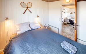 A neatly made bed with a quilted cover, two pillows, and a folded shirt on the bed. There is a tennis racket hanging on the wall above the bed. - 2 bedroom cozy home in Hjørring (Hjørring)