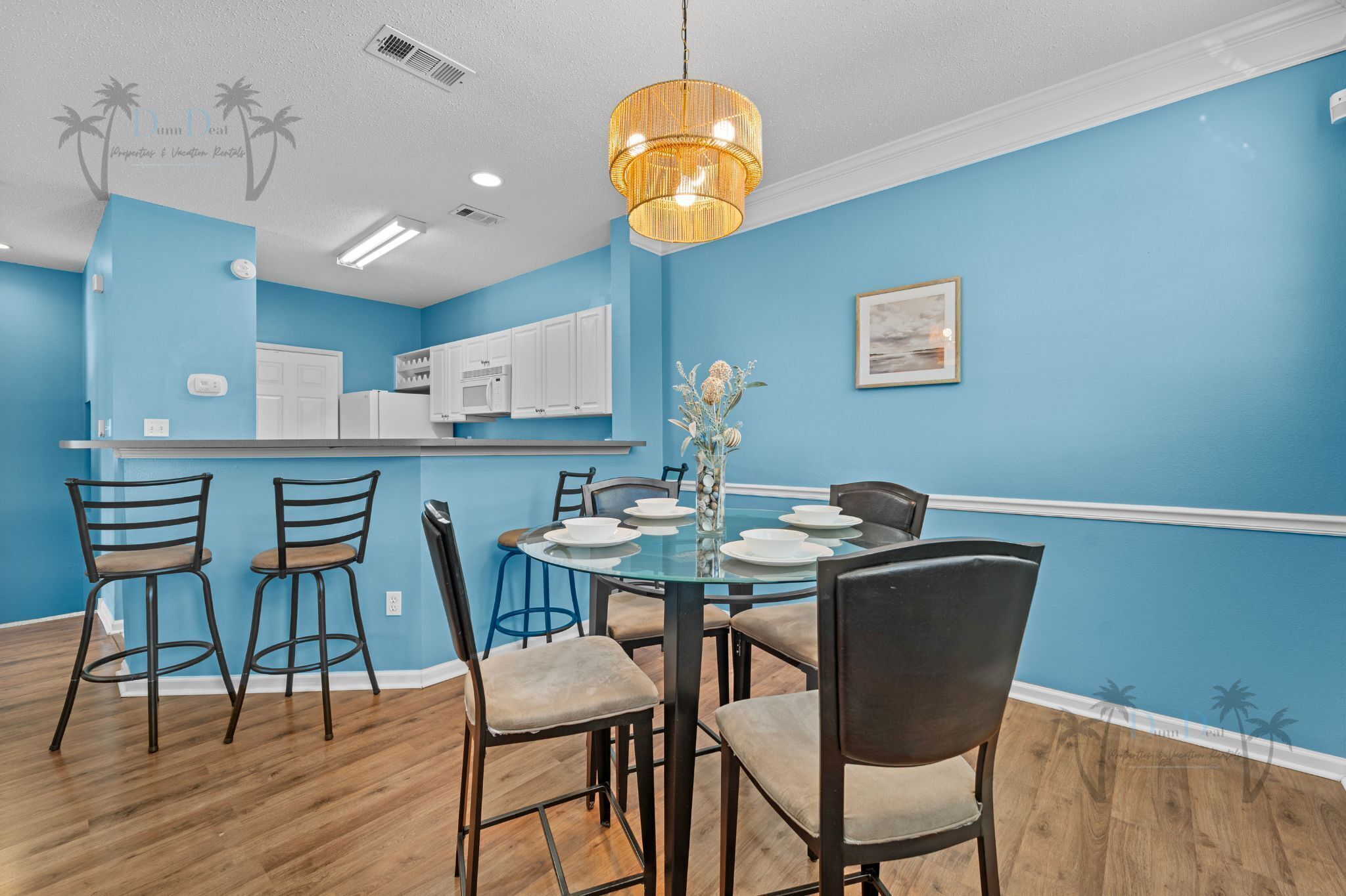 A dining area with a round table, chairs, and a hanging light fixture.