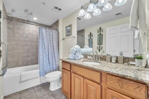 A bathroom with a bathtub, toilet, vanity with a sink, and a large mirror. - Legacy Tower II 206 | Stunning Coastal Views! (Gulfport)