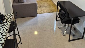 Uma sala de estar com sofá, televisão, escrivaninha e janela.