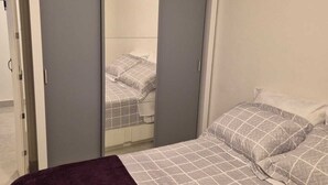 Um quarto com uma cama, um guarda-roupa e um espelho.