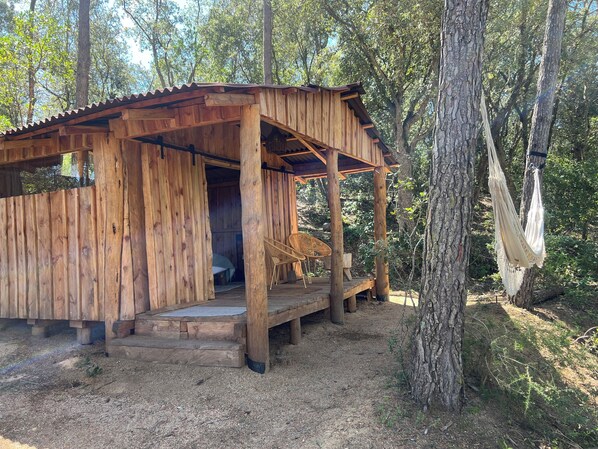 Una cabaña de madera con porche, una hamaca y una silla.