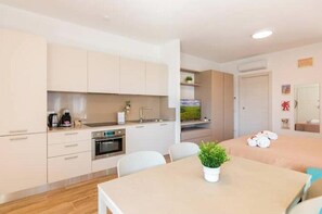 Eine moderne Küche mit weißen Schränken, einem eingebauten Backofen und einem Essbereich mit Tisch und Stühlen.
