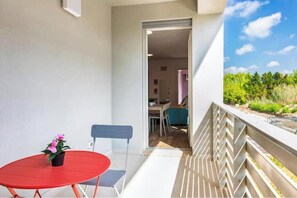 A balcony with a red table and chairs, a potted plant, and a view of a garden. - Studio Apartment with Double Balcony - 900 m from Tower, Private Park (Pisa)