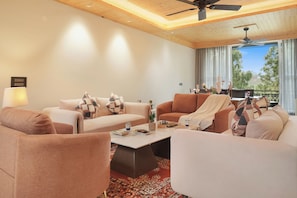 A modern living room with a ceiling fan, a coffee table, and two sofas with patterned cushions. - ELIVAAS 4 BHK Kavya Villa With Lounge  (Kasauli)