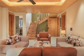 A modern living room with a wooden staircase, two sofas, and a coffee table. - ELIVAAS 4 BHK Kavya Villa With Lounge  (Kasauli)