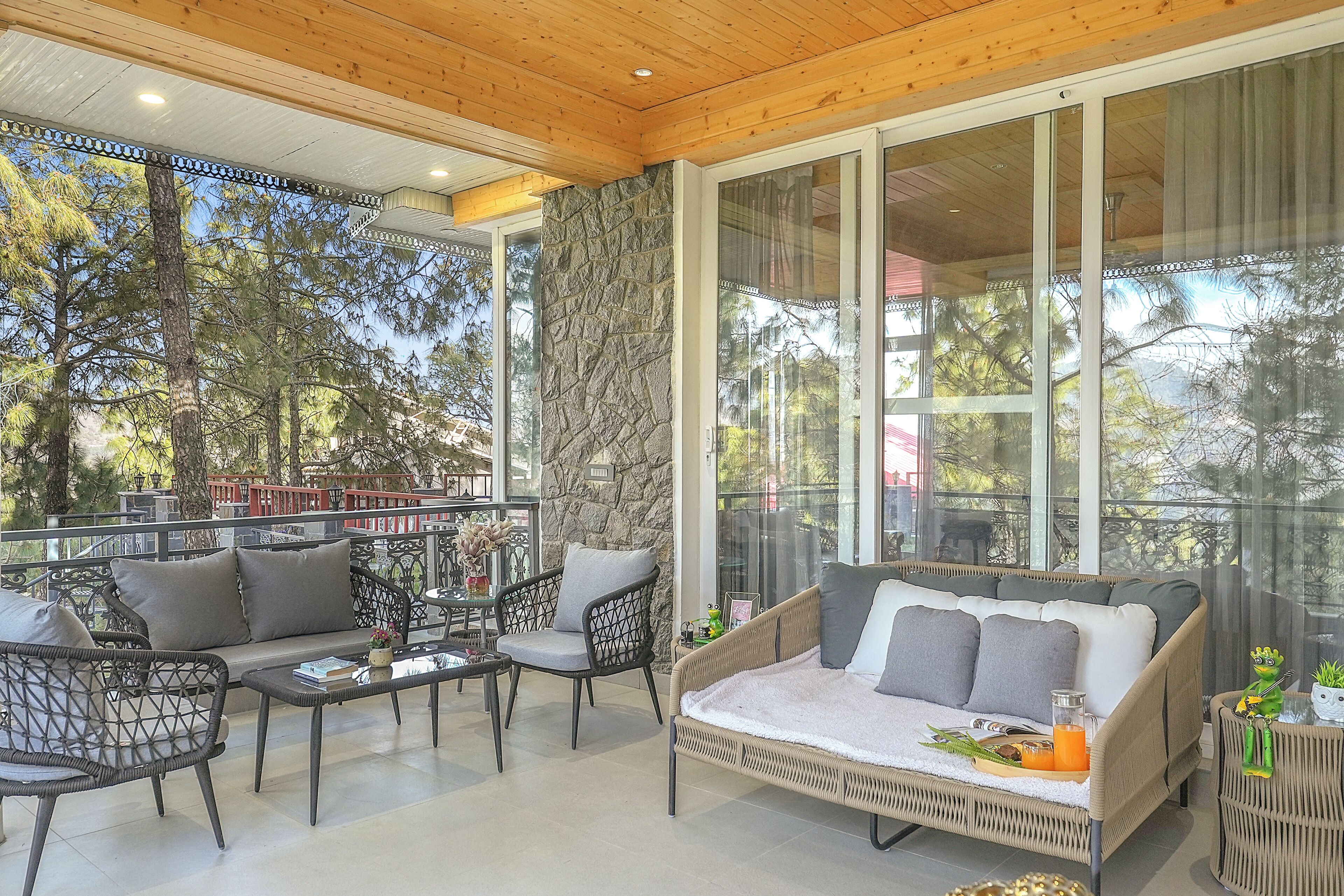 A modern outdoor living area with a sofa, chairs, a table, and a stone wall.