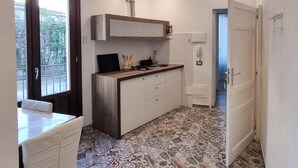 Een kleine keuken met een houten aanrecht, een inbouwspoelbak en vloertegels met een patroon.