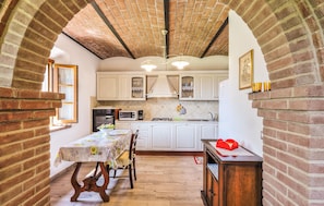 A kitchen with white cabinets, a brick archway, and a dining table with chairs. - 3 bedroom gorgeous home in Montecatini Val Di Cec (Montecatini Val Di Cec)