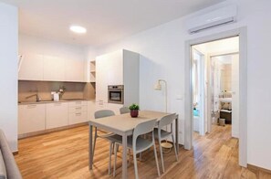 A modern kitchen with white cabinets, a dining table with chairs, and a small plant on the table. - Apartment with Balcony - 900 m from Tower, Private Park & Modern Comfort (Pisa)