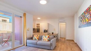 Un appartement moderne avec un canapé gris, un coin repas et une cuisine.