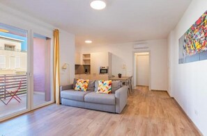 A modern apartment with a grey sofa, a dining area, and a kitchen. - Apartment with Balcony - 900 m from Tower, Private Park & Modern Comfort (Pisa)