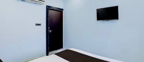 Una habitación con una cama, aire acondicionado, una puerta y un televisor.