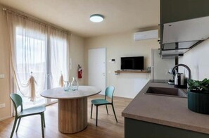 A modern kitchen with a built-in oven, a sink, and a television. - Studio Apartment with Balcony Tower View - New, 900 m from Center (Pisa)