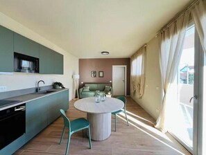 A modern kitchen with a dining area, a sofa, and a large window. - Studio Apartment with Balcony Tower View - New, 900 m from Center (Pisa)