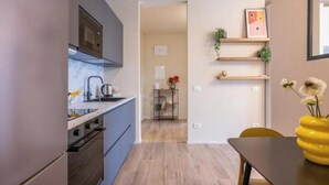 Eine moderne Küche mit eingebautem Ofen, ein Essbereich mit Tisch und Stühlen und ein Gang zu einem weiteren Raum.