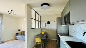 Eine moderne Küche mit eingebauter Mikrowelle, ein Essbereich mit Tisch und Stühlen sowie ein Sofa im angrenzenden Wohnzimmer.