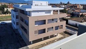 A multi-story building with balconies, a flat roof, and a clear view of the surrounding neighborhood. - New Apartment with Balcony - Near Tower, Private Park (Pisa)