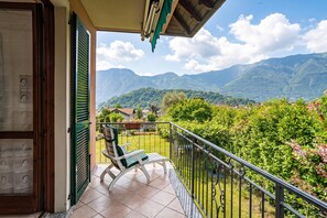 Un balcon avec vue sur les montagnes, une chaise et une rambarde.