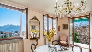A dining area with a table set for two, a chandelier, a mirror, and a view of the outside. - Lenno Il Guscio (Tremezzina)