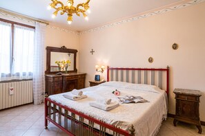 Une chambre à coucher comprenant un lit, une commode, un miroir, une fenêtre avec des rideaux et un lustre.