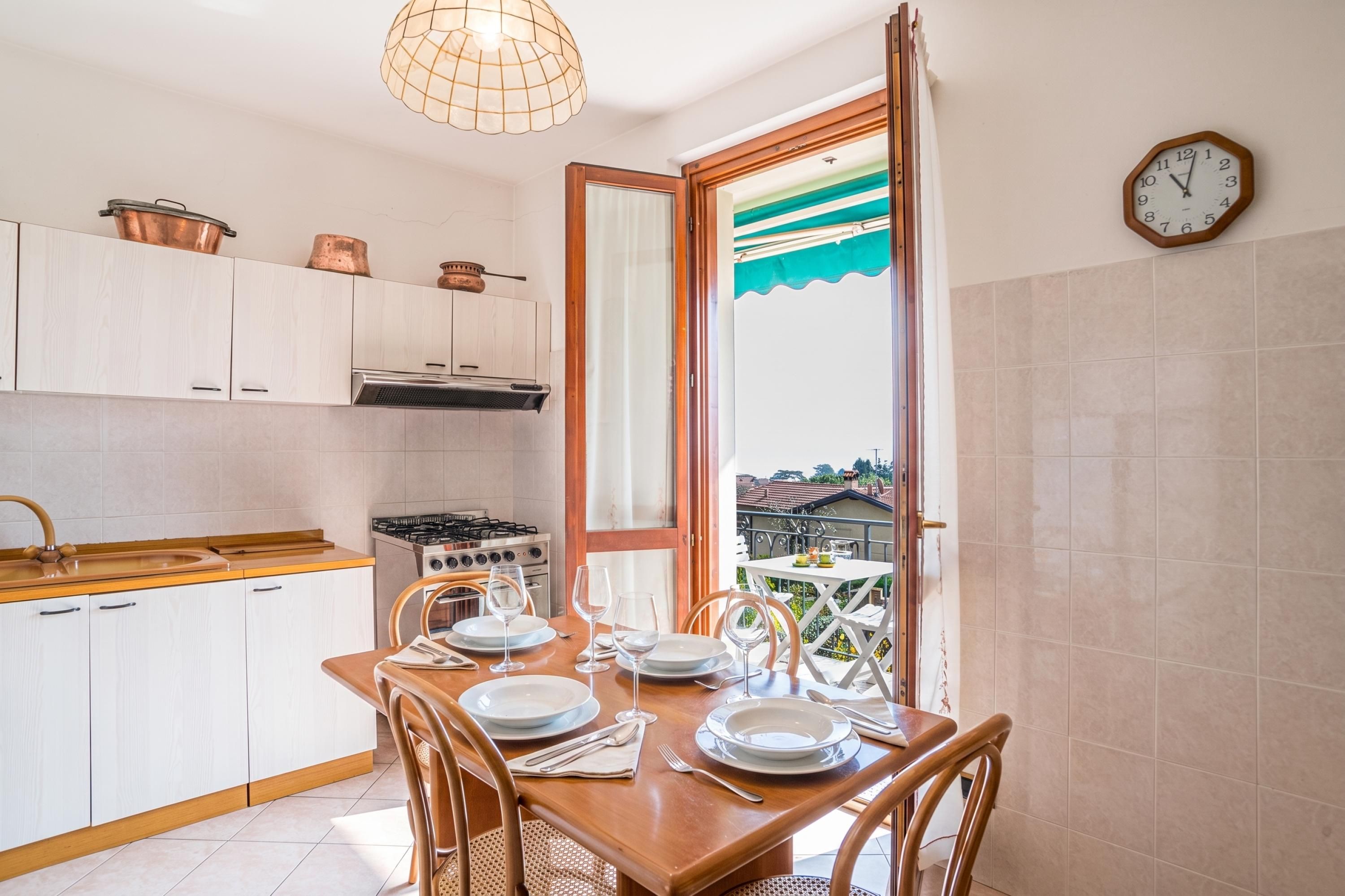 A kitchen with white cabinets, a stove, and a dining table set for four with plates, glasses, and cutlery.