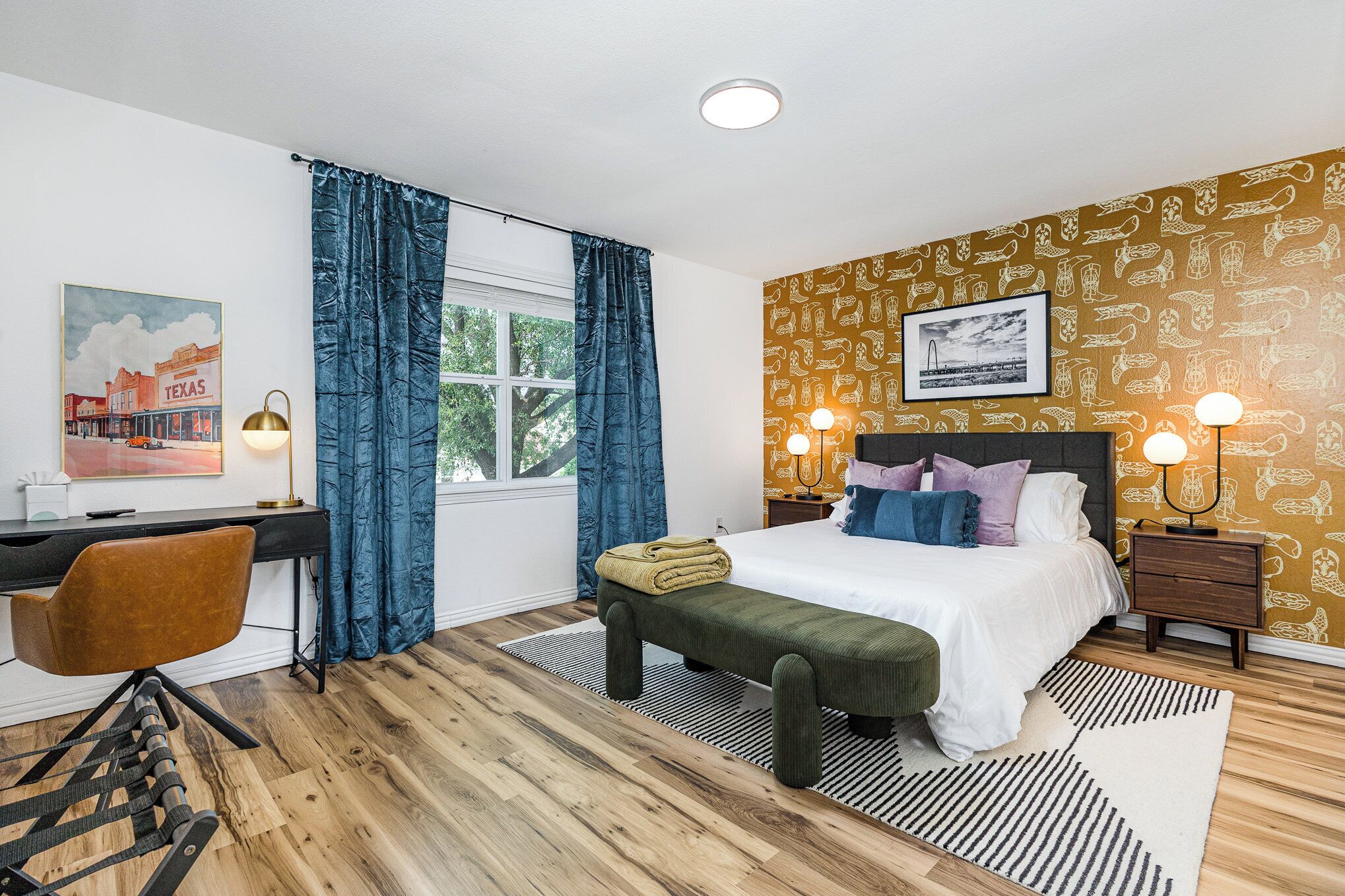A bedroom with a bed, desk, chair, and a window with curtains.