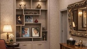 A well-lit room with a red armchair, a bench, a console table, a wall-mounted mirror, and a built-in shelving unit with various decorative items. - Urban nest old Tbilisi (Tbilisi)