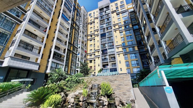 A multi-story residential building with balconies, a small waterfall feature, and a green awning. - 3-bedroom apartment in wonderful Nairobi with indoor pool and garden (Nairobi)