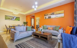 A living room with a sofa set, a coffee table, and a dining area with chairs and a table.