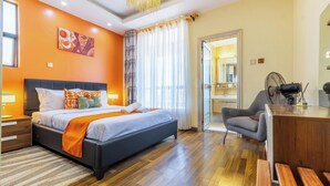 A hotel room with a bed, a desk, a chair, a mirror, and a window with curtains. - 3-bedroom apartment in wonderful Nairobi with indoor pool and garden (Nairobi)