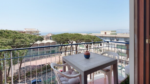 A balcony with a table and chairs, overlooking a street and buildings. - Apartment 'Le Stelle Di Zia Pina' with Sea View, Wi-Fi and Air Conditioning (Torre del Greco)