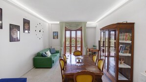 A dining area with a wooden table, chairs, a green sofa, and a cabinet with books. - Apartment 'Le Stelle Di Zia Pina' with Sea View, Wi-Fi and Air Conditioning (Torre del Greco)