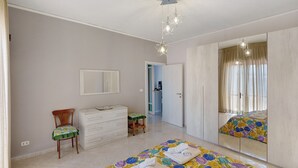 A bedroom with a bed, a dresser, a chair, a mirror, and a door leading to another room. - Apartment 'Le Stelle Di Zia Pina' with Sea View, Wi-Fi and Air Conditioning (Torre del Greco)