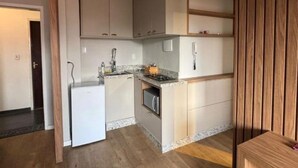 Eine moderne Küche mit weißen Schränken, einem eingebauten Backofen und einem kleinen Kühlschrank.