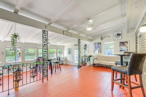 A spacious indoor area with a high ceiling, a red-tiled floor, and a seating area with chairs and a table. - Gym, Office! Extended Base 8 Mi to Marietta Square (Marietta)