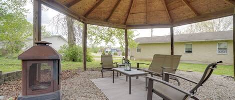 An outdoor patio with a covered area, a wood-burning stove, and seating.