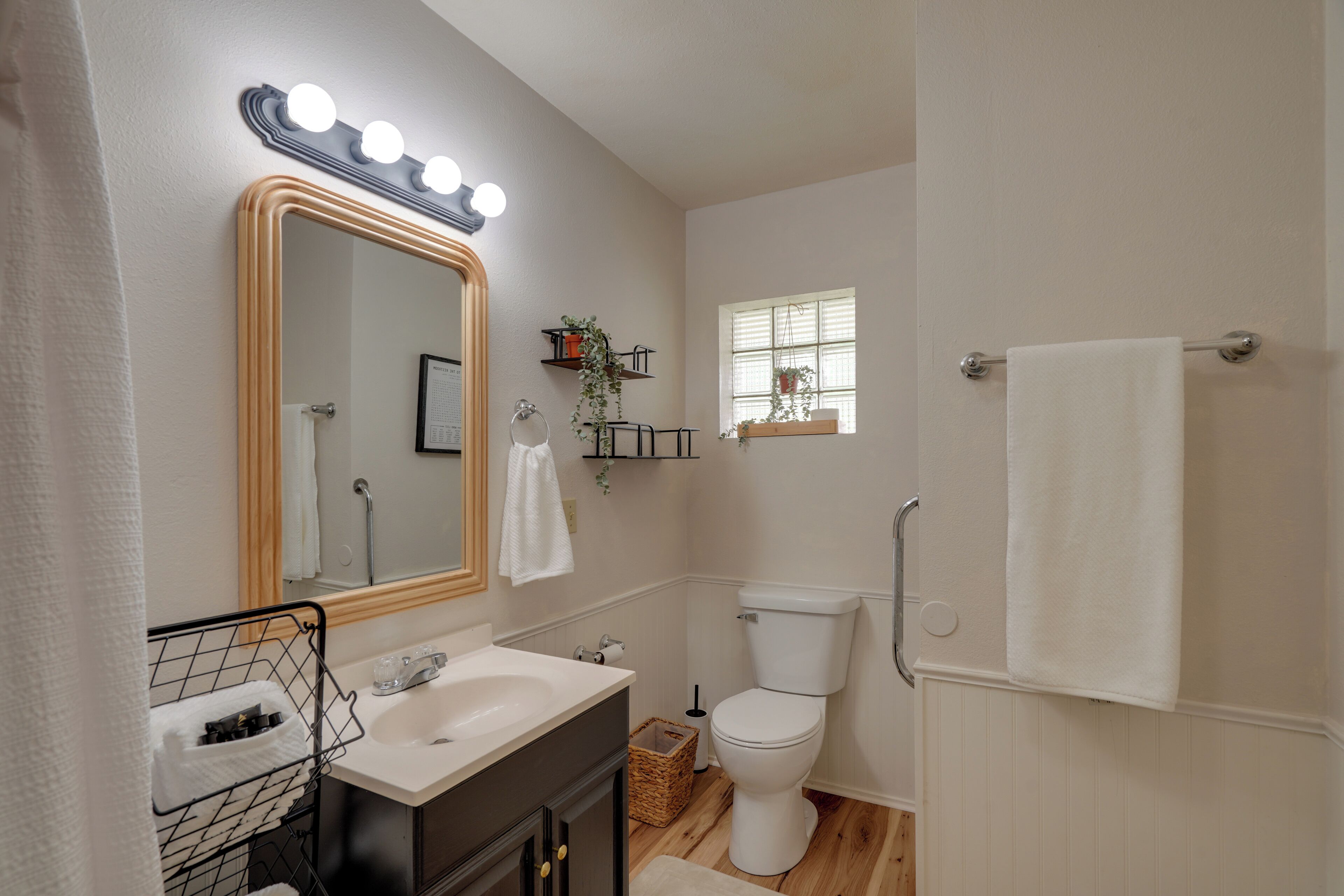 Un bagno con un mobile lavabo, lavandino, specchio illuminato, WC e una finestra.