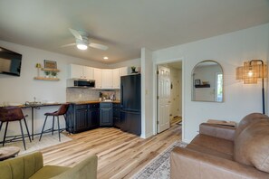 A modern kitchen with white cabinets, a black refrigerator, and a dining area with a bar stool. - 5 Mi to Elephant Rocks State Park Condo (Ironton)