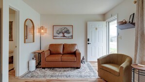 A living room with a brown sofa, a patterned rug, a small table, a wall-mounted light, and a door with a number. - 5 Mi to Elephant Rocks State Park Condo (Ironton)