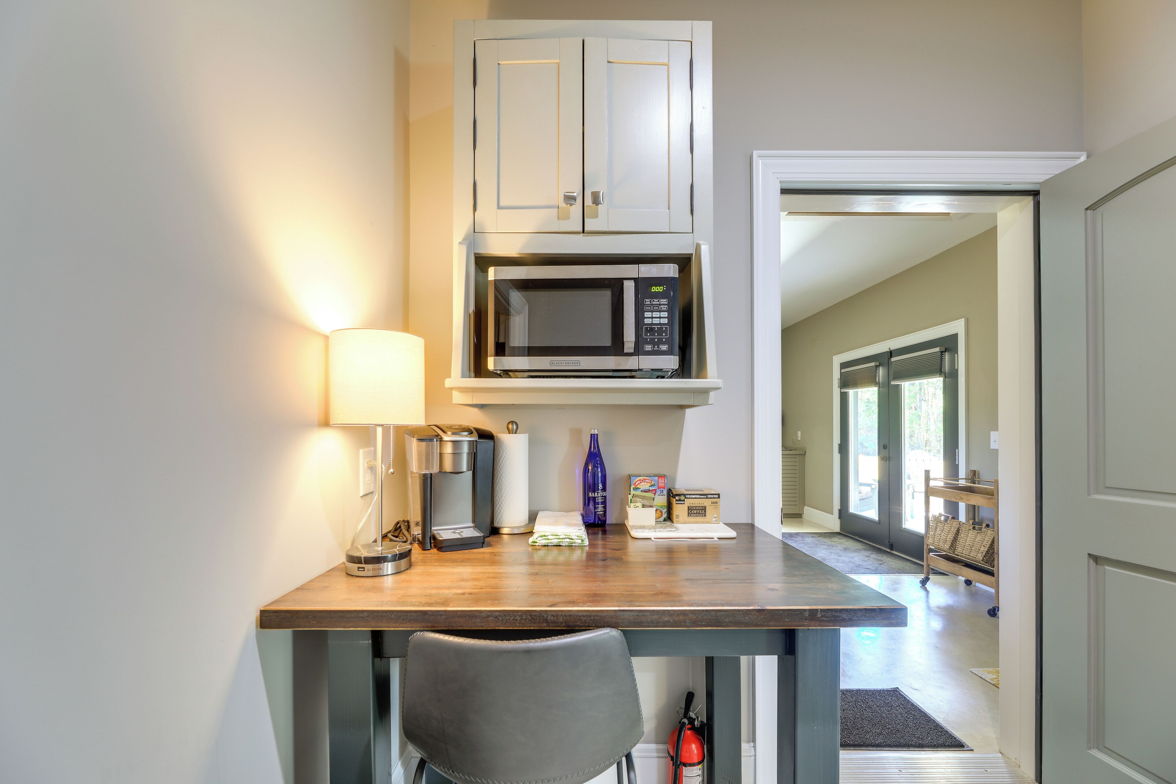 A kitchenette with a microwave, coffee maker, and a lamp.