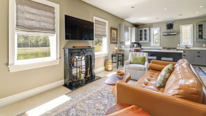 A spacious living room with a fireplace, a sofa, and a television. - Patio w/ Pond & Forest Views! Havelock Retreat (Havelock)