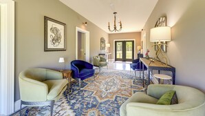 A spacious living area with a patterned carpet, two armchairs, a sofa, a chandelier, and a table with a lamp. - Patio w/ Pond & Forest Views! Havelock Retreat (Havelock)