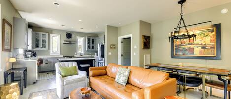 A modern living room with a leather sofa, wooden coffee table, and a dining area with a table and chairs.