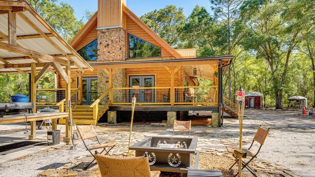 A wooden cabin with a stone fireplace, outdoor seating, and a covered porch. - Fish & Float at Natural Springs! Log Cabin in Bell (Bell)