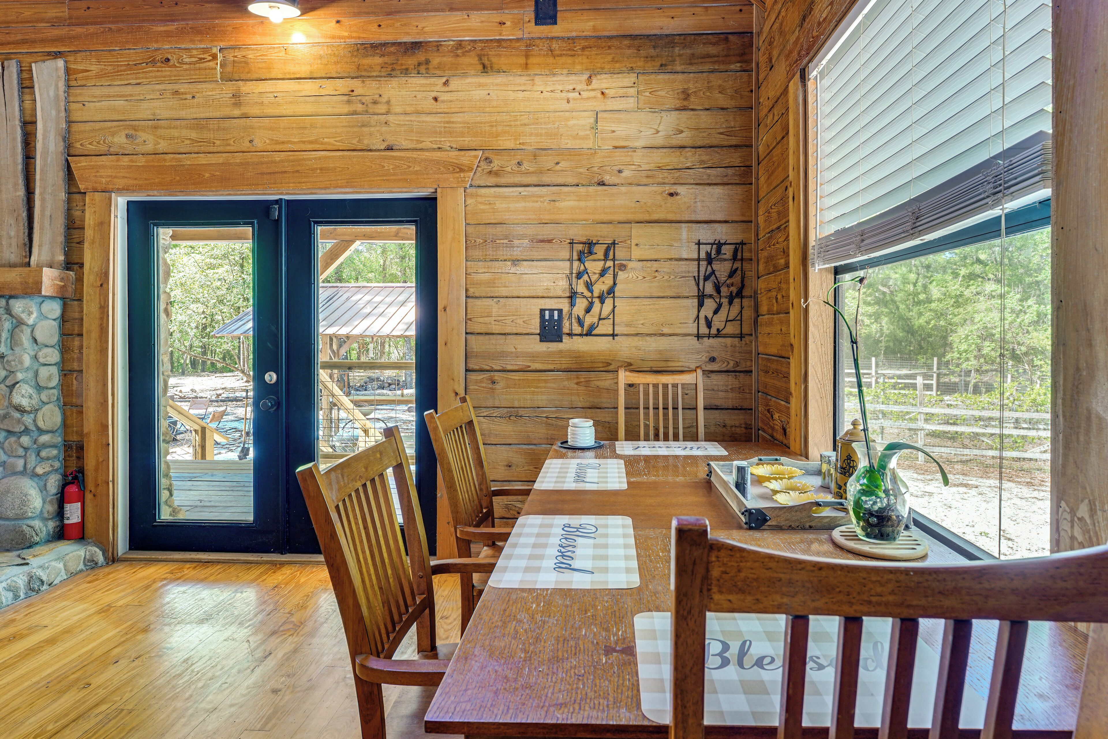 Un interior de madera con una mesa de comedor, sillas, una chimenea y vistas al exterior.