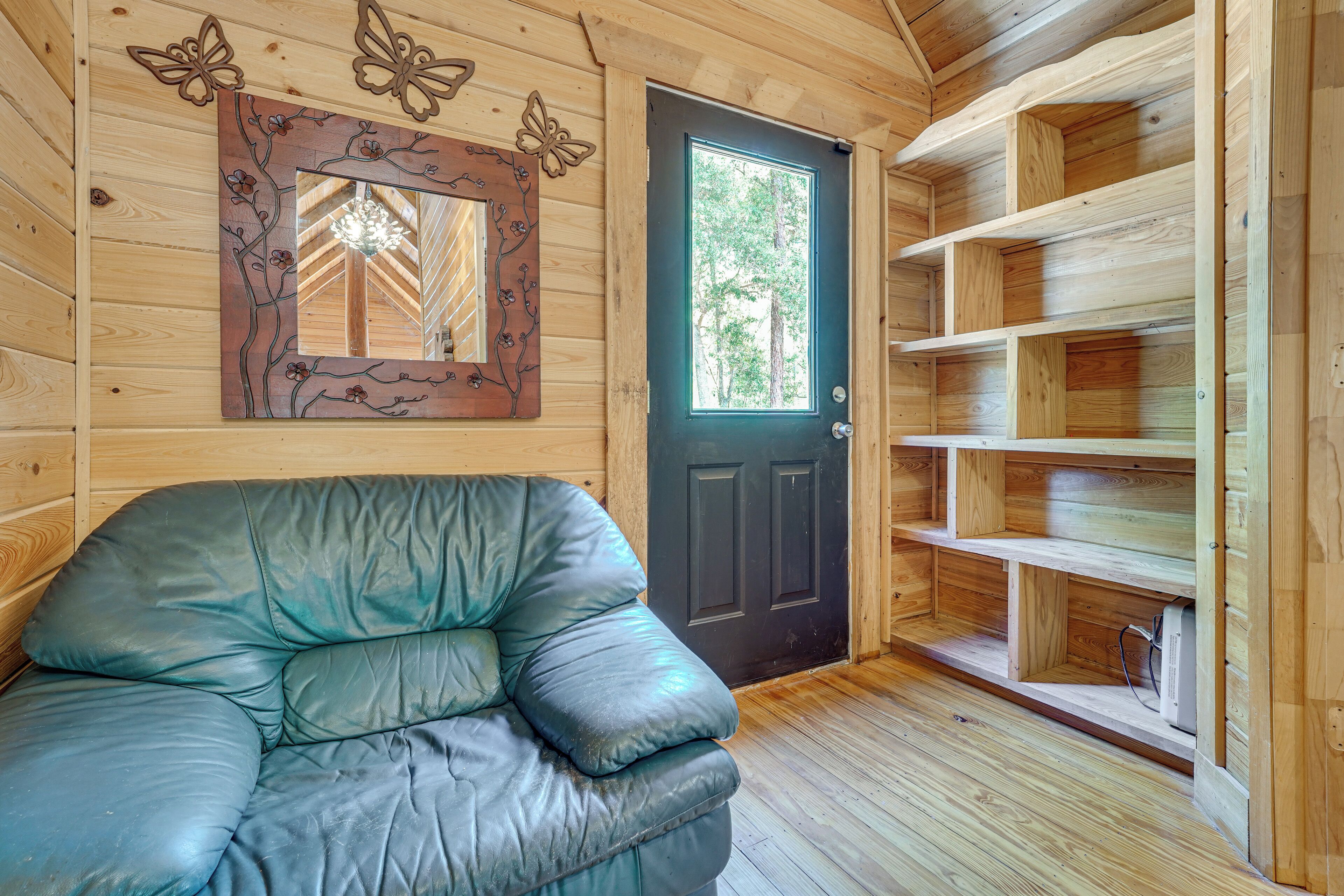 Un interior de madera con una puerta negra, un sofá de cuero y estanterías de madera.