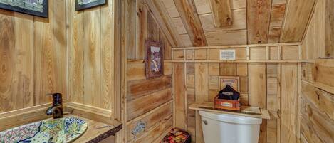 Ein Badezimmer aus Holz mit Waschbecken, Toilette und Mülleimer.