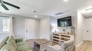 Una sala de estar con sofá, sillón, mesa de centro, televisor y estantería.