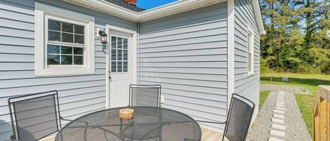 A patio with a round table and chairs, a door, and a window.